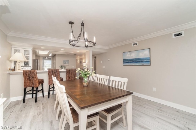 dining area featuring light hardwood / wood-style floors, crown molding, and a notable chandelier