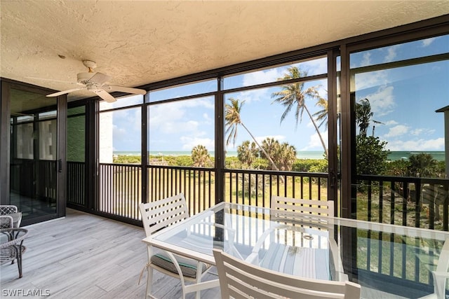 sunroom / solarium featuring ceiling fan and a water view