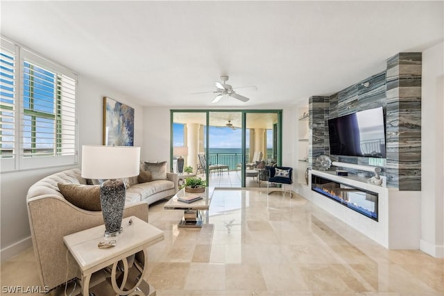 living area featuring a wealth of natural light, baseboards, a large fireplace, and a ceiling fan