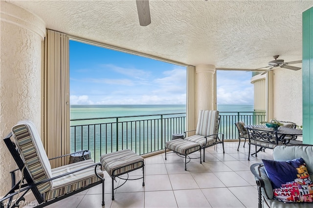 balcony with ceiling fan and a water view