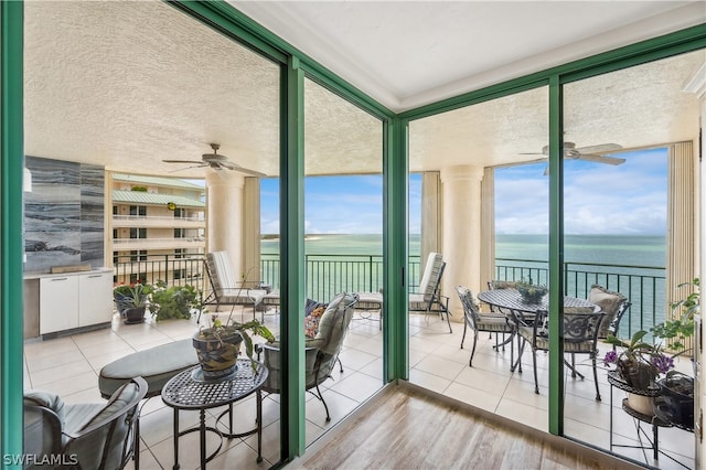 sunroom / solarium featuring a wealth of natural light, ceiling fan, and a water view