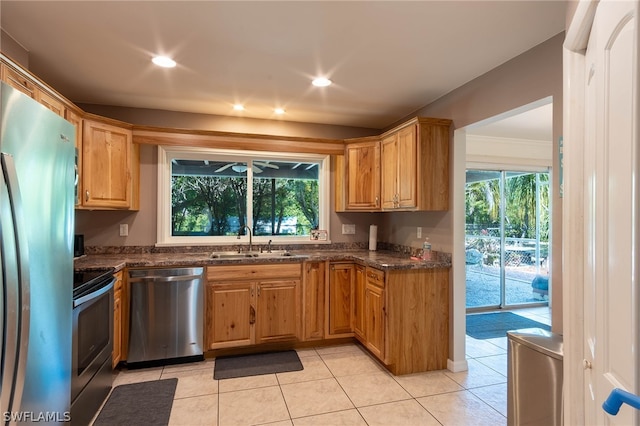 kitchen featuring a wealth of natural light, sink, appliances with stainless steel finishes, and dark stone countertops