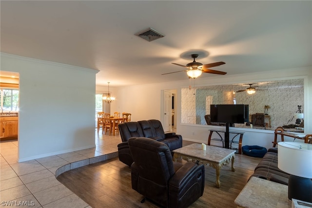 tiled living room with crown molding and ceiling fan with notable chandelier