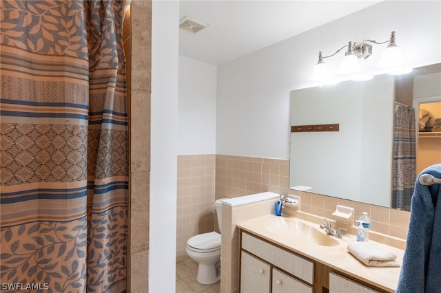 bathroom featuring curtained shower, toilet, tile patterned floors, tile walls, and vanity