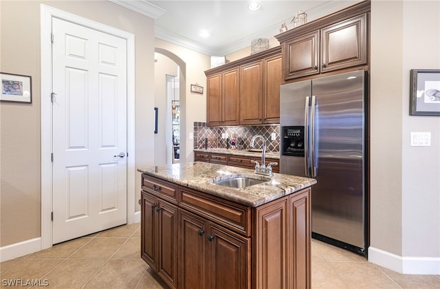 kitchen with an island with sink, sink, stainless steel fridge with ice dispenser, light tile patterned floors, and crown molding