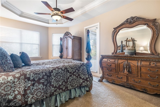 bedroom featuring ceiling fan, a raised ceiling, light colored carpet, and multiple windows