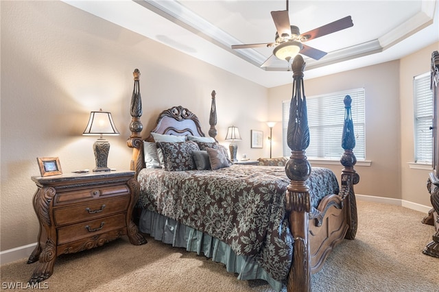 bedroom featuring ceiling fan, a raised ceiling, light carpet, and multiple windows