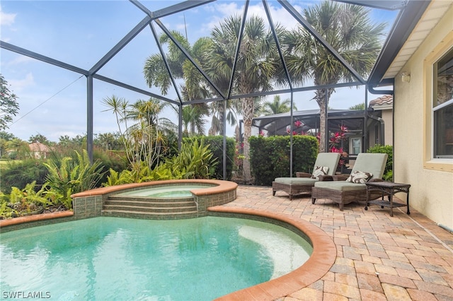 view of pool featuring glass enclosure, an in ground hot tub, and a patio