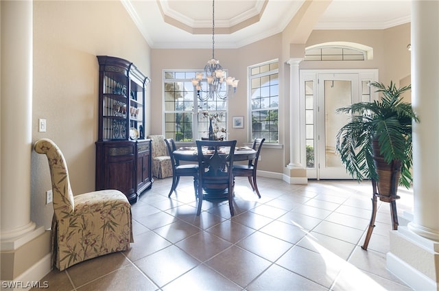 dining space with decorative columns, a raised ceiling, and ornamental molding