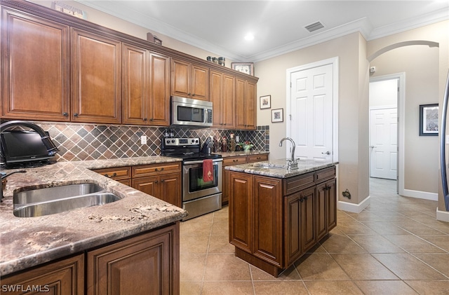 kitchen featuring sink, crown molding, a center island with sink, and stainless steel appliances