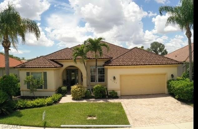 mediterranean / spanish-style home with a garage and a front lawn