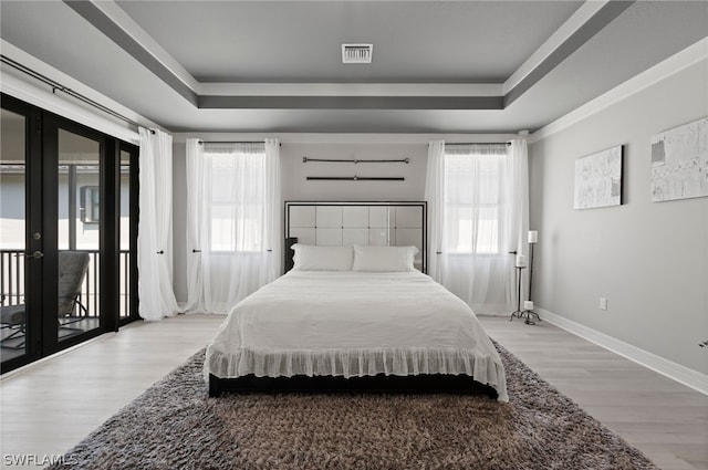 bedroom featuring french doors, light hardwood / wood-style floors, multiple windows, and access to outside