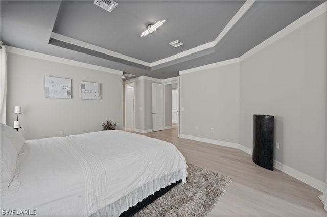 bedroom with light hardwood / wood-style floors and a raised ceiling