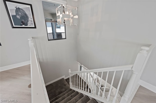 stairway featuring hardwood / wood-style floors and an inviting chandelier