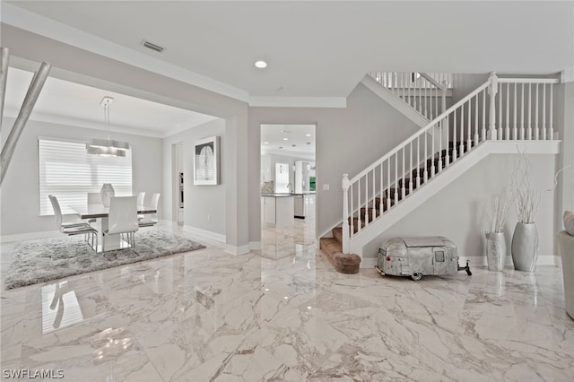 entrance foyer with a notable chandelier, ornamental molding, and a wealth of natural light