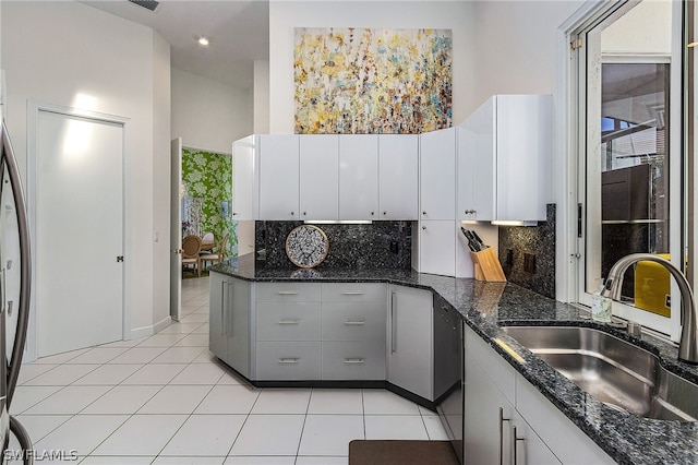 kitchen with backsplash, gray cabinetry, dark stone countertops, and sink