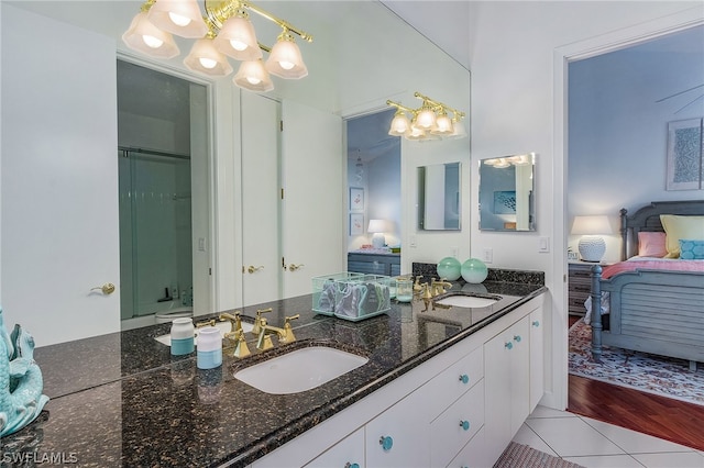 bathroom with tile flooring, walk in shower, a chandelier, and dual bowl vanity