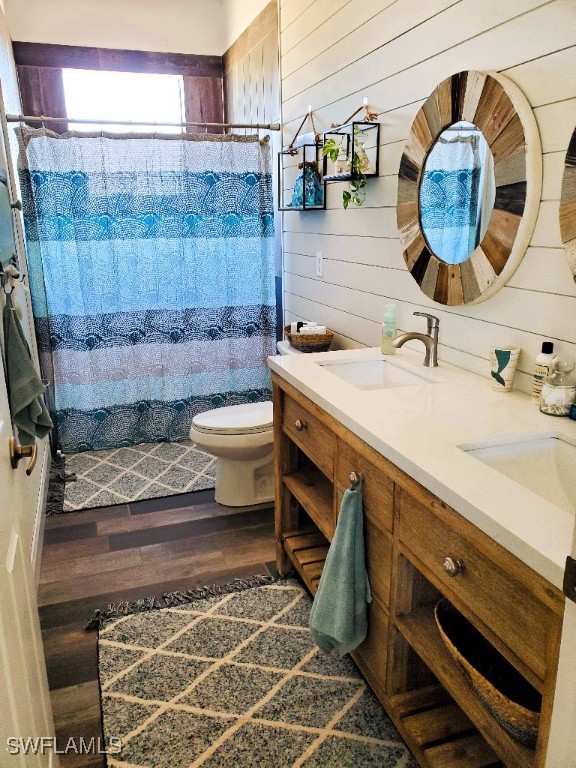 bathroom featuring vanity, wood walls, toilet, and hardwood / wood-style floors