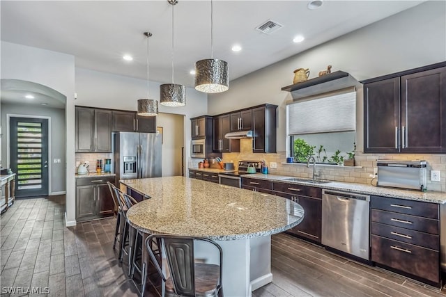 kitchen with sink, hanging light fixtures, a kitchen breakfast bar, a kitchen island, and stainless steel appliances