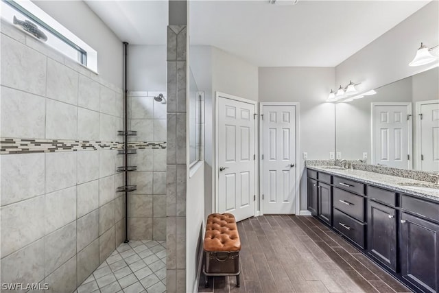 bathroom featuring vanity, wood-type flooring, and tiled shower