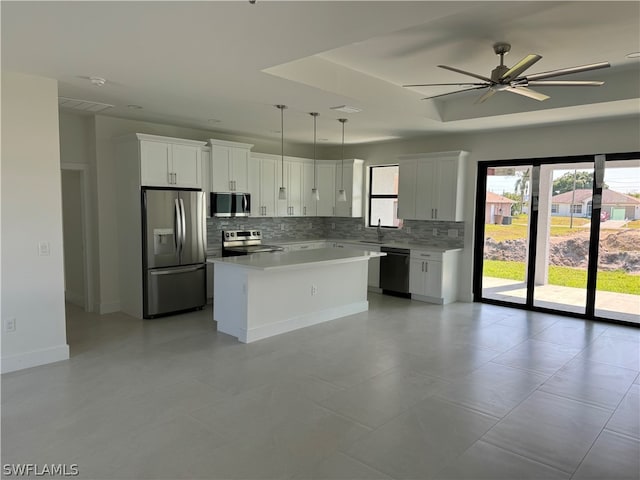 kitchen featuring decorative light fixtures, ceiling fan, stainless steel appliances, tasteful backsplash, and a center island