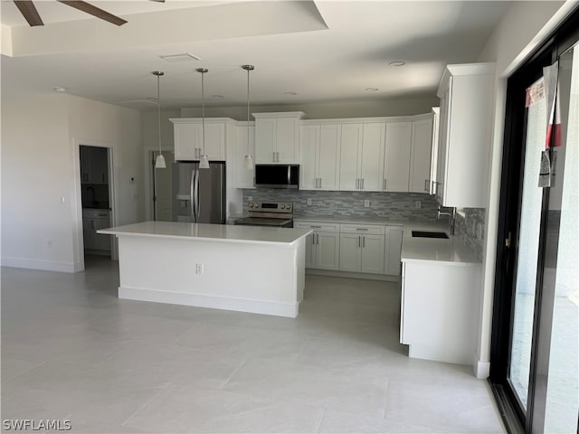 kitchen with hanging light fixtures, white cabinetry, stainless steel appliances, sink, and ceiling fan