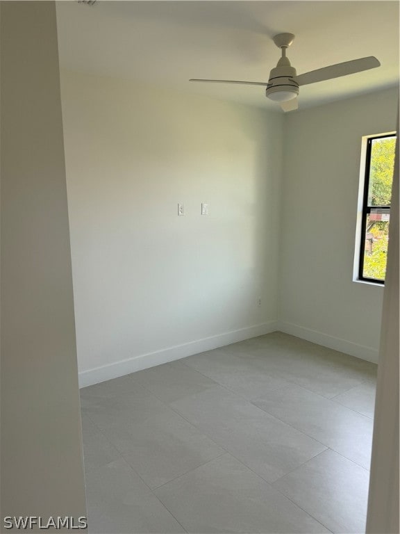 tiled spare room featuring ceiling fan