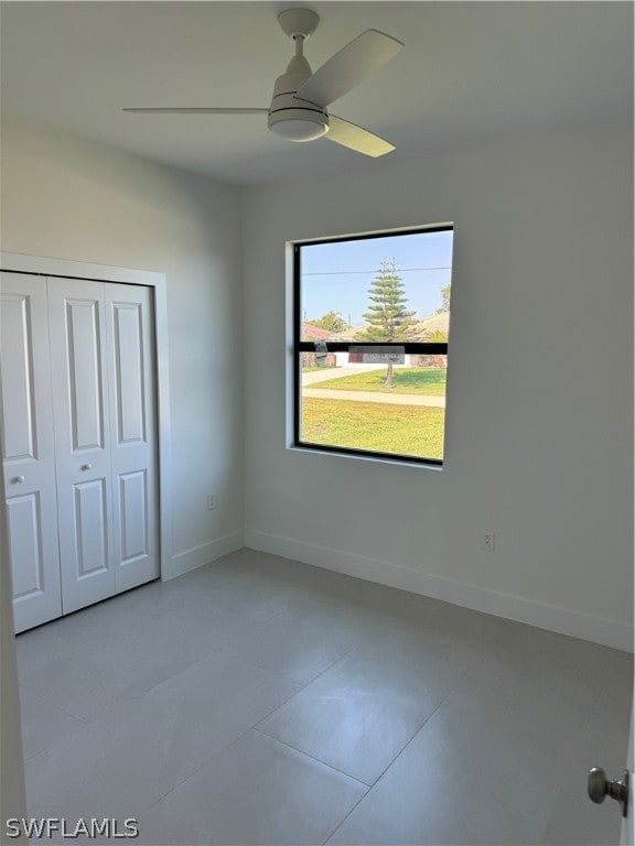 unfurnished bedroom with ceiling fan, tile flooring, and a closet