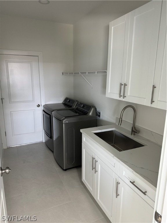 laundry area featuring sink, washer and clothes dryer, cabinets, and light tile floors