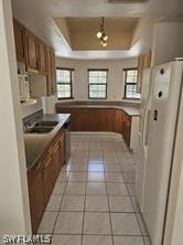 kitchen with sink, light tile flooring, a raised ceiling, and white fridge