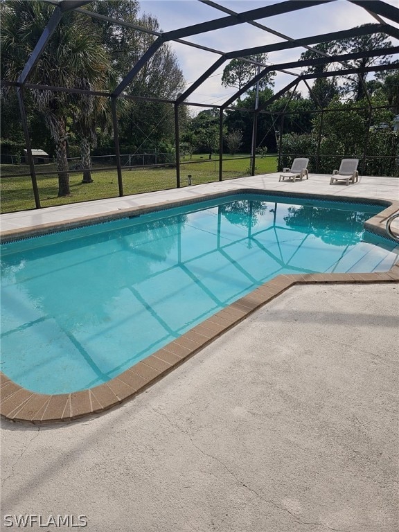 view of swimming pool featuring a lawn, a lanai, and a patio