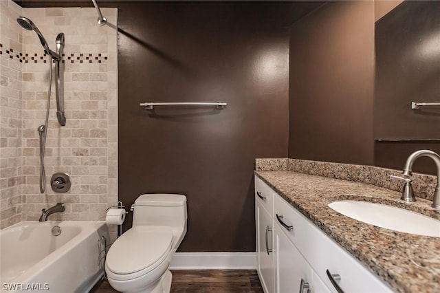 full bathroom with hardwood / wood-style floors, tiled shower / bath, vanity, and toilet