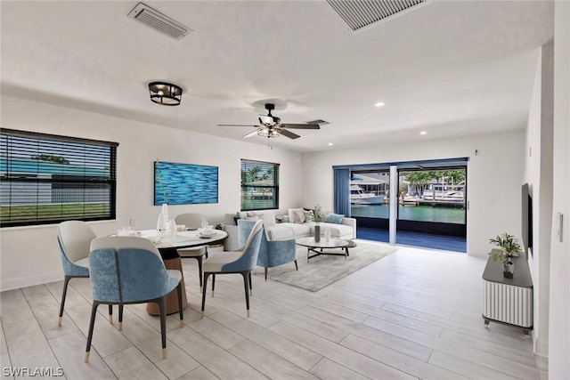 dining space with plenty of natural light, a water view, ceiling fan, and light hardwood / wood-style flooring