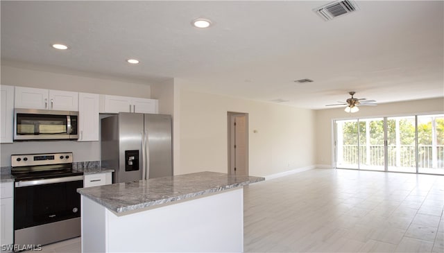 kitchen with ceiling fan, stainless steel appliances, a center island, and white cabinetry