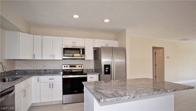 kitchen with sink, appliances with stainless steel finishes, a center island, and white cabinetry