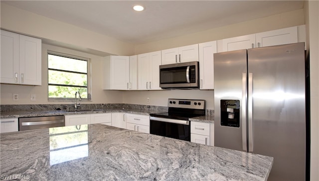 kitchen with sink, white cabinetry, stainless steel appliances, and light stone counters