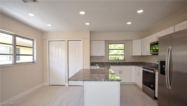 kitchen with white cabinets, sink, appliances with stainless steel finishes, and a kitchen island