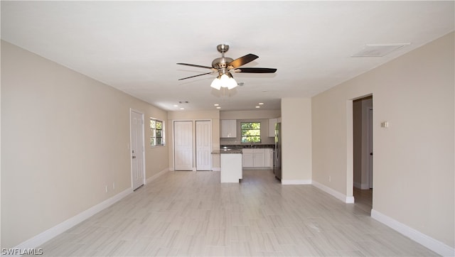 unfurnished living room with ceiling fan and light tile floors