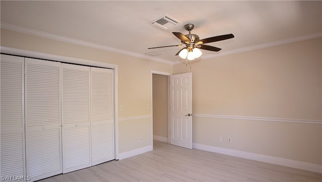 unfurnished bedroom with crown molding, a closet, ceiling fan, and light wood-type flooring