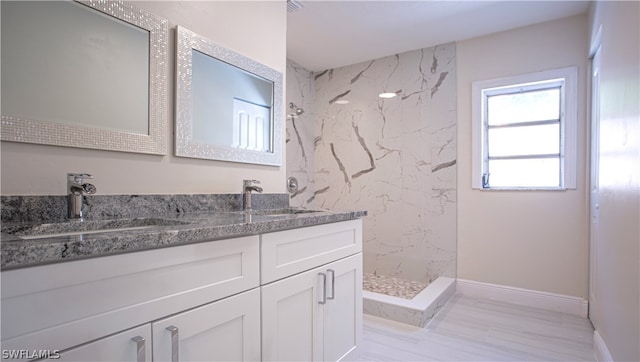 bathroom with tiled shower and double vanity