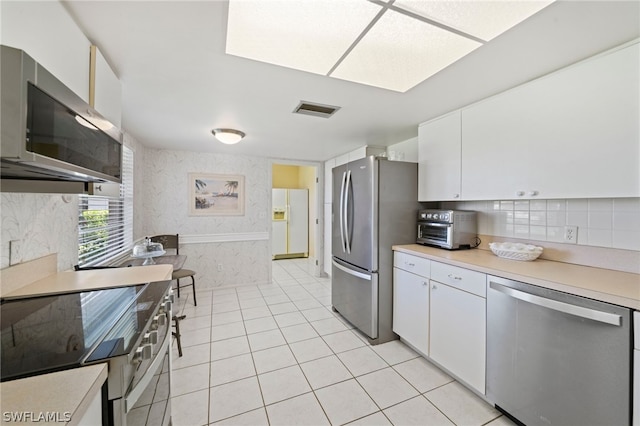 kitchen featuring appliances with stainless steel finishes, white cabinets, tasteful backsplash, and light tile floors