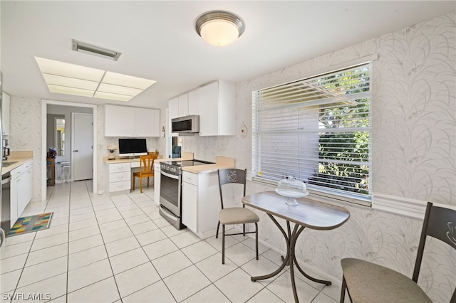 kitchen with white cabinetry, stove, and light tile floors