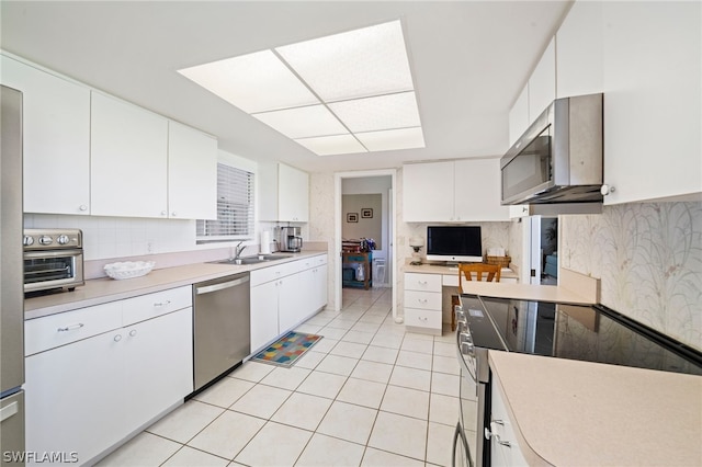 kitchen featuring white cabinetry, range, tasteful backsplash, dishwasher, and light tile floors