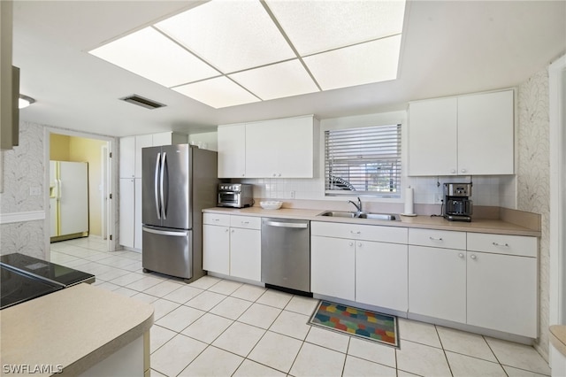 kitchen featuring stainless steel appliances, white cabinets, light tile flooring, and backsplash