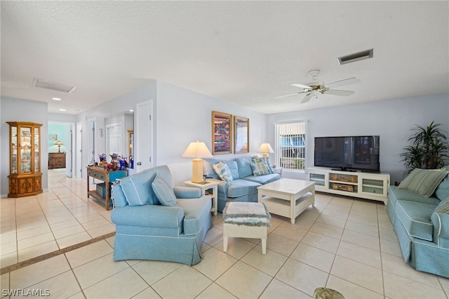 living room with ceiling fan, a textured ceiling, and light tile flooring