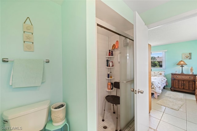 bathroom with tile flooring, an enclosed shower, and toilet