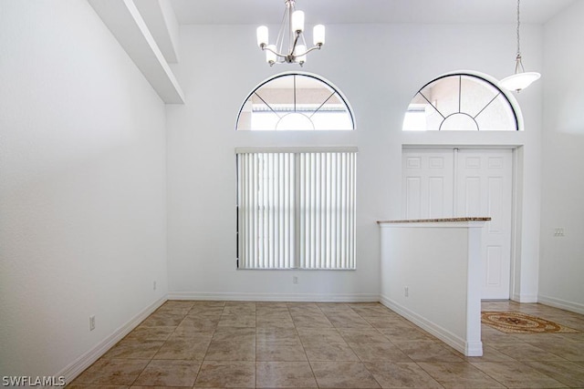 interior space featuring a towering ceiling, light tile patterned flooring, and an inviting chandelier