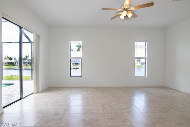 tiled spare room with ceiling fan and a water view