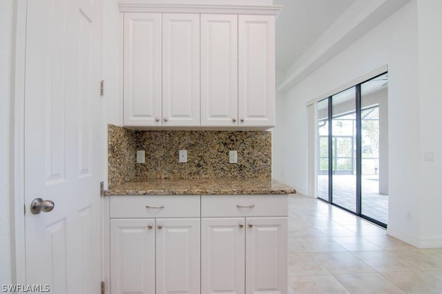 kitchen with tasteful backsplash, light stone counters, white cabinets, and light tile patterned flooring