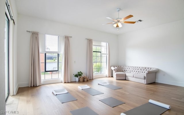 exercise room with light wood-type flooring and ceiling fan